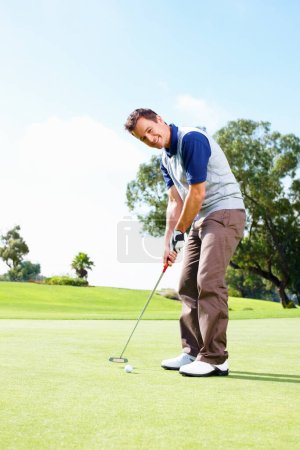 Foto de Golfista sonriente poniendo la pelota. Longitud completa de hombre sonriente jugando al golf y poniendo la pelota - Imagen libre de derechos