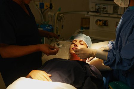 Photo for Expert medical care from an expert medical team. a surgeon preparing a patient for her surgery - Royalty Free Image