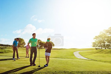 Téléchargez les photos : Sortir avec des amis sur le fairway. deux couples jouant une partie de golf ensemble par une journée ensoleillée - en image libre de droit