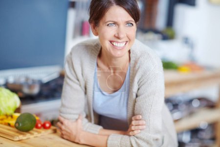 Téléchargez les photos : Il est temps d'expérimenter dans la cuisine. une jolie femme appuyée sur un comptoir de cuisine rempli de légumes - en image libre de droit