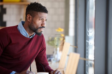 Photo for Its a great place to clear your head. A young african man sitting in a coffee shop - Royalty Free Image