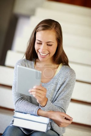 Foto de Un poco de relajación antes de ir a los libros. Una mujer joven usando una tableta digital mientras está sentada en una escalera en casa - Imagen libre de derechos