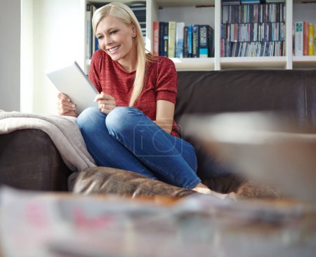Photo for Enjoying a good book on the weekend. an attractive young woman sitting on a couch while using a digital tablet - Royalty Free Image
