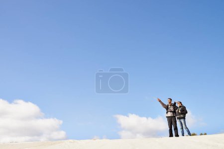 Téléchargez les photos : Fixer un objectif. un couple heureux en randonnée dans les dunes ensemble - en image libre de droit