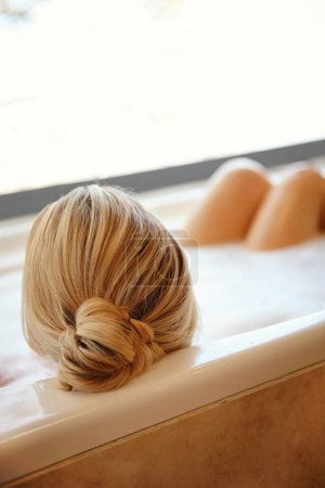 Téléchargez les photos : Des moments sereins. Une jeune femme heureuse se relaxant dans un bain de mousse luxueux - en image libre de droit