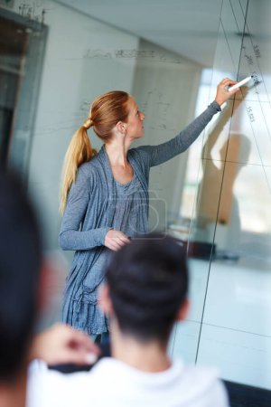 Photo for Plotting their projected profit margin. Attractive casual businesswoman giving a presentation using a glass window for demonstration - Royalty Free Image