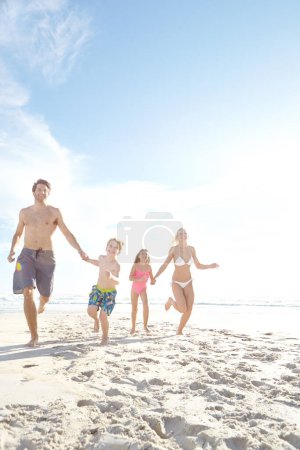 Foto de Siempre es más divertido con tu familia. una familia joven y feliz disfrutando de un día soleado en la playa - Imagen libre de derechos