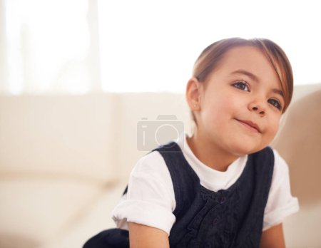 Photo for Im gonna be a big girl one day. Closeup shot of an adorable little girl sitting on a sofa and looking thoughtful - Royalty Free Image