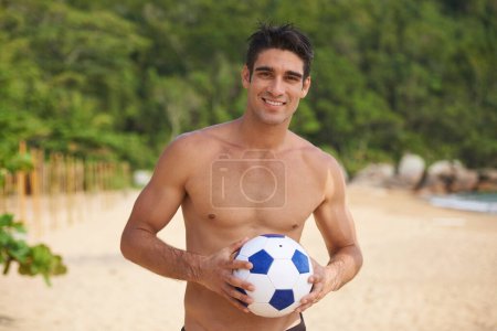 Photo for Beach soccer - whos in. A portrait of a handsome young man with a soccer ball on the beach - Royalty Free Image