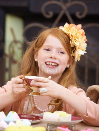 Foto de Recuerdos de la infancia. Linda chica pelirroja sosteniendo una taza de té y jugando a disfrazarse - Imagen libre de derechos