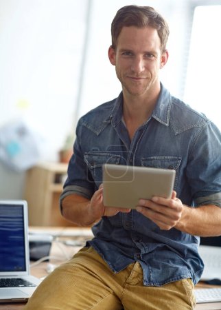 Téléchargez les photos : Rattraper les courriels avant le travail. Un jeune homme lisant ses SMS debout dans son bureau - en image libre de droit