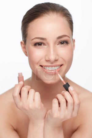 Photo for Loving the natural look. Cropped portrait of a gorgeous young woman applying lipgloss with a smile - Royalty Free Image