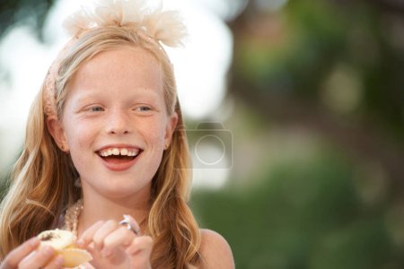 Foto de Sabrosas golosinas de cumpleaños. Un poco de firl comiendo una magdalena y riendo - copyspace - Imagen libre de derechos