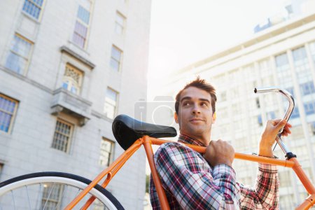 Téléchargez les photos : Je voyage à la mode. un bel homme voyageant à vélo dans la ville - en image libre de droit