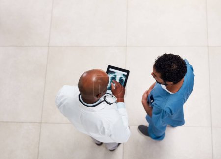 Téléchargez les photos : Alors, quelle est notre prochaine étape ? Plan grand angle de deux jeunes médecins discutant sur une tablette numérique à l'intérieur d'un hôpital - en image libre de droit