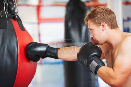 Slamming the bag. A young boxer practicing with a punching ball at the gym