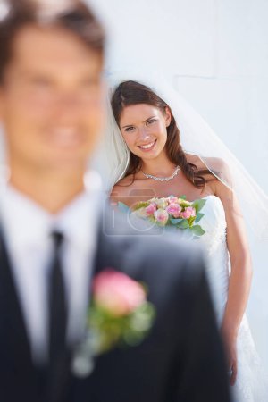 Téléchargez les photos : Elle se tient derrière lui. Une mariée étonnante souriant joyeusement tandis que son futur mari se tient flou au premier plan - en image libre de droit