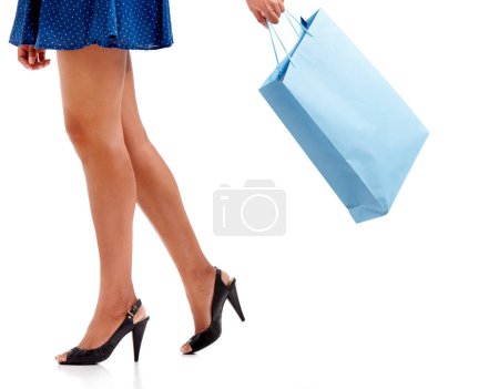 Téléchargez les photos : Un bon achat. Un gros plan d'une femme jambes en talons tenant un sac à provisions - en image libre de droit