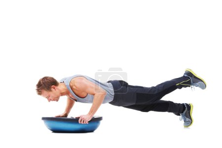 Photo for Hes working towards improved levels of fitness. A young man working his upper body using a bosu-ball - Royalty Free Image