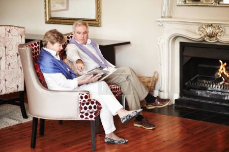 Téléchargez les photos : Détente au coin du feu. Un couple de personnes âgées se relaxant au coin du feu pendant les vacances - en image libre de droit