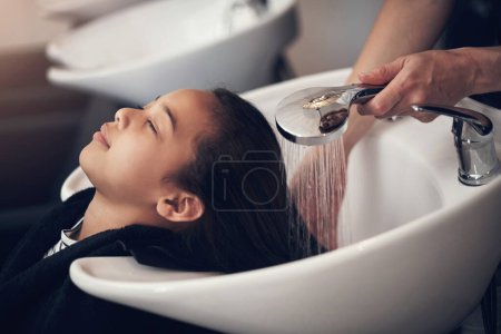 Foto de La peluquera es un lugar encantador y relajante para ir. una joven que se lava el pelo en el salón - Imagen libre de derechos
