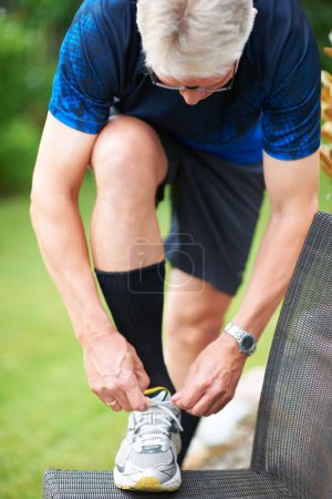Téléchargez les photos : Des lacets solides sont des joggeurs meilleurs amis. un joggeur posant son pied sur une chaise tout en attachant son lacet - en image libre de droit