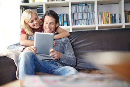 Photo for Getting excited while planning their vacation. an attractive young woman embracing her boyfriend while he uses a digital tablet - Royalty Free Image