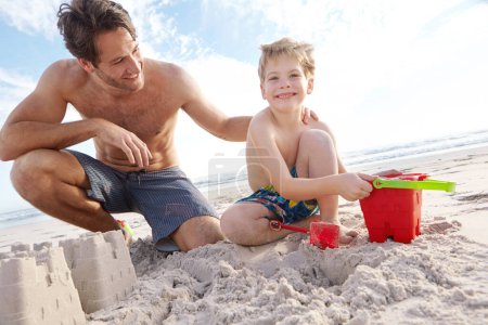 Téléchargez les photos : Du temps entre père et fils. un jeune père et son fils construisant un château de sable sur la plage - en image libre de droit