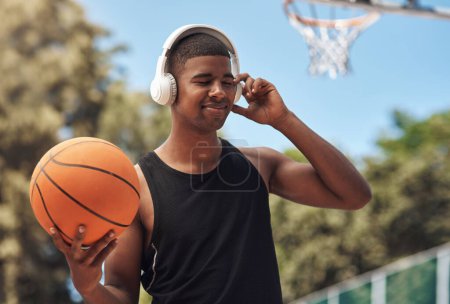 Photo for Music preps me for greatness. a sporty young man listening to music while playing basketball on a sports court - Royalty Free Image