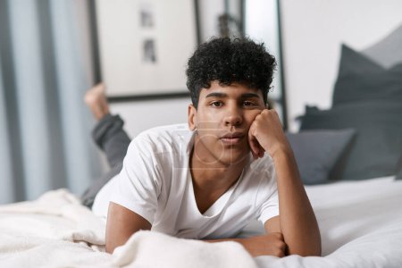 Foto de La cuarentena es una gran estación de aislamiento. un joven acostado en su cama y que parece aburrido - Imagen libre de derechos