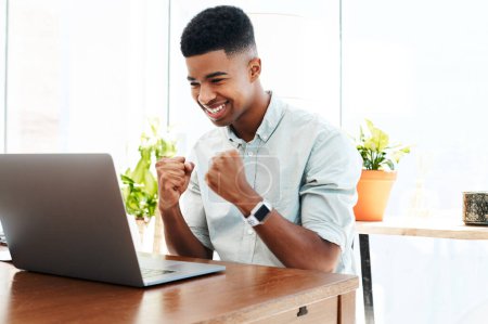 Foto de El trabajo duro siempre gana. un joven hombre de negocios animando mientras usa un portátil en una oficina moderna - Imagen libre de derechos