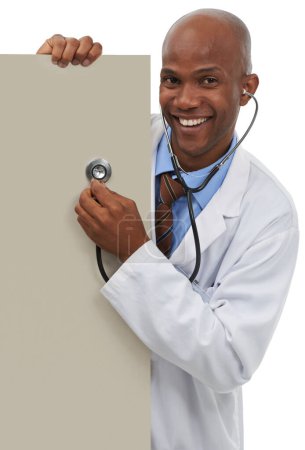 Photo for Endorsing your healthcare message. A young doctor holding a stethoscope up to a board reserved for copyspace - Royalty Free Image