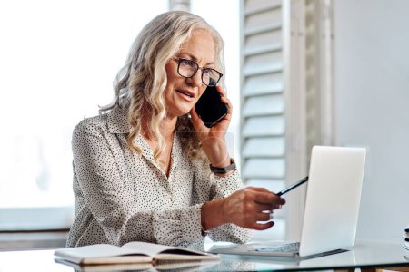Photo for Are you talking about the latest report. an attractive senior businesswoman taking a phonecall while working from home - Royalty Free Image