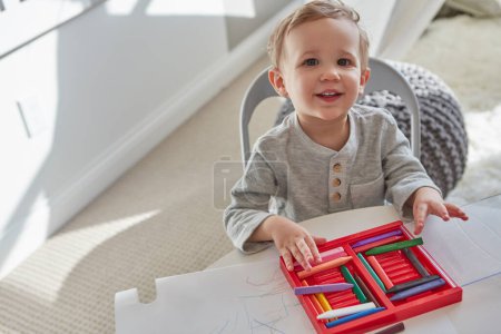 Foto de Siempre está buscando sus lápices de colores y papel. un niño jugando con sus crayones en casa - Imagen libre de derechos