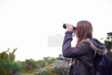 Téléchargez les photos : Fouiller le ciel et les paysages. une jeune femme séduisante regardant à travers des jumelles pendant une randonnée - en image libre de droit