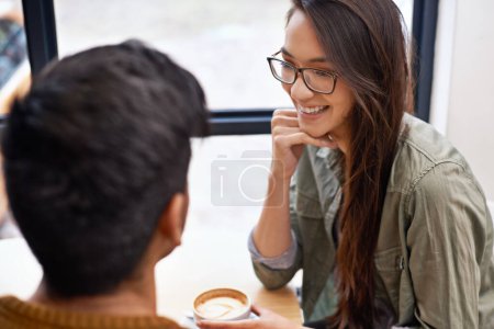 Foto de Él la hace reír. una joven pareja sentada en una cafetería en una cita - Imagen libre de derechos