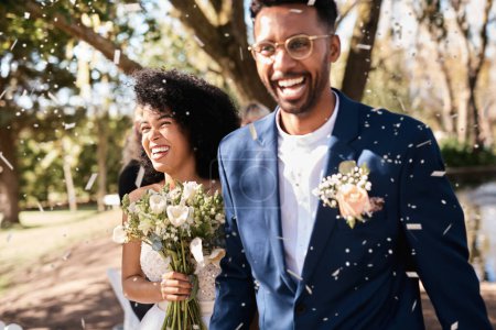 Téléchargez les photos : Jour de mariage, couple et confettis en plein air avec bonheur et sourire de l'événement de mariage. Célébration, peuple africain et mariée marchant avec bouquet de fleurs lors de la cérémonie d'engagement d'amour et de confiance. - en image libre de droit