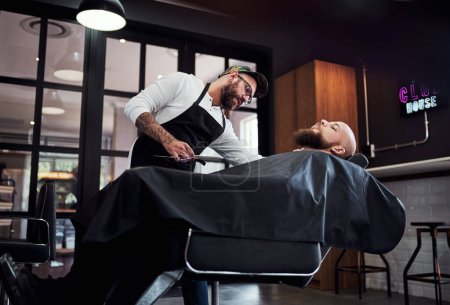 Photo for Sit still and relax, Ill handle the rest. a handsome young barber trimming and lining up a clients beard inside his barbershop - Royalty Free Image