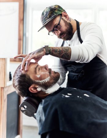Foto de Siempre me ha apasionado esta profesión. un hombre maduro guapo que se corta la barba y se alinea en una barbería - Imagen libre de derechos