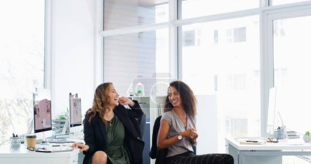 Photo for Lighten the mood, lighten the workload. two young businesswomen chatting at their desks in a modern office - Royalty Free Image