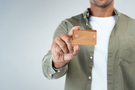 Téléchargez les photos : Je vais faire quelques achats. un homme méconnaissable tenant sa carte de crédit debout sur un fond gris - en image libre de droit