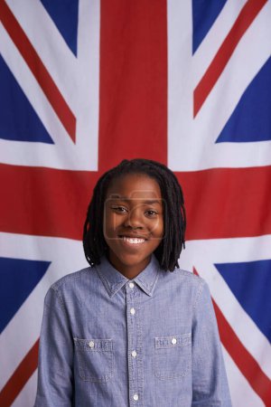 Photo for God save the queen. Portrait of a happy young boy standing in front of the Union Jack - Royalty Free Image