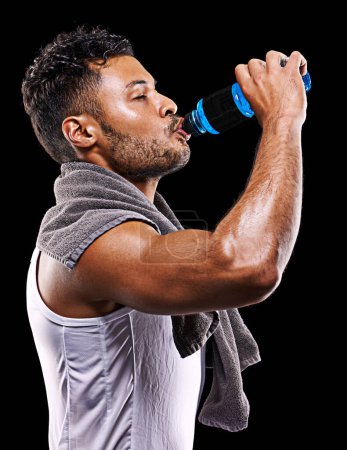 Téléchargez les photos : Rester hydraté. Plan studio d'un beau jeune homme en tenue de sport buvant dans sa bouteille d'eau - en image libre de droit