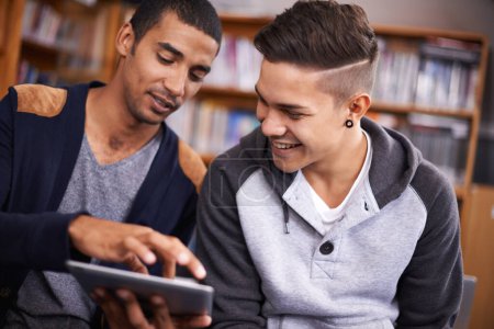 Foto de Esta es la mejor parte. dos jóvenes mirando una tableta digital en la biblioteca universitaria - Imagen libre de derechos