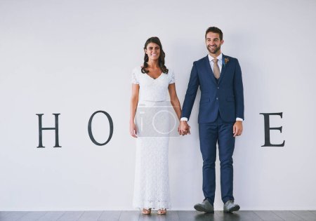 Photo for Forever beings today. Concept studio shot of a bride and groom making an M in the word home against a wall - Royalty Free Image