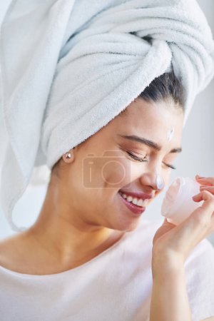 Photo for This smell gets me all the time. a beautiful young woman applying moisturizer to her skin in the bathroom at home - Royalty Free Image