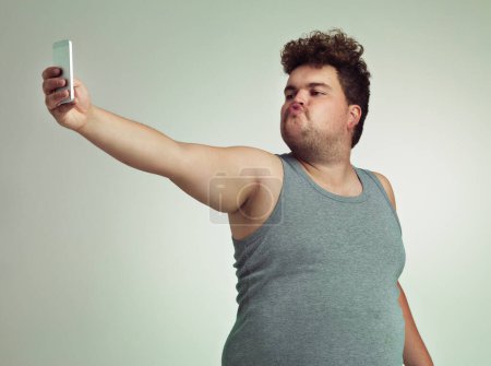 Foto de Un beso. un hombre con sobrepeso tomando una selfie mientras hace pucheros - Imagen libre de derechos