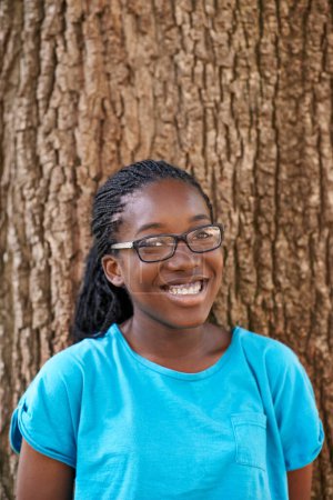 Photo for Shes not a tree hugger but she sure loves em. Portrait of a teenager smiling while standing against a tree - Royalty Free Image