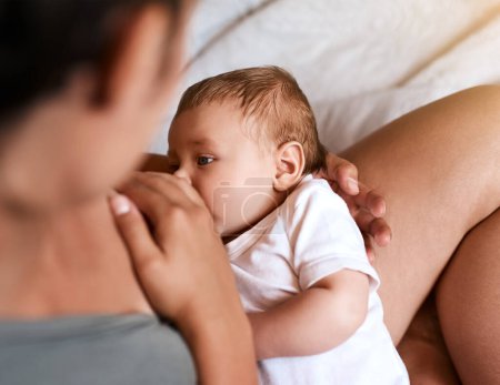 Photo for Hes a hungry boy. High angle shot of a young mother breastfeeding her newborn baby at home - Royalty Free Image