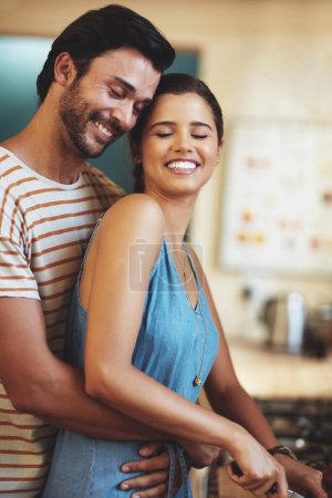 Téléchargez les photos : L'amour rend tout beau. un jeune couple affectueux cuisiner ensemble dans leur cuisine à la maison - en image libre de droit